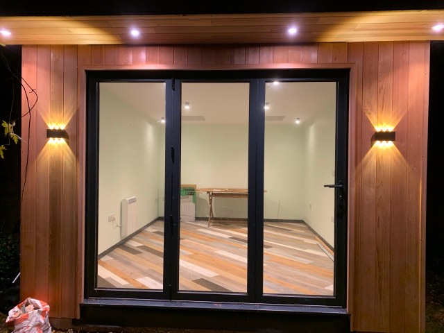 Garden room lit at night with warm exterior up and down lights