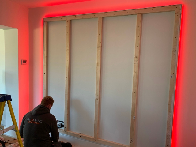 A Two Gang electrician on a stepladder, fitting concealed LED lighting into a stud wall during a fit-out